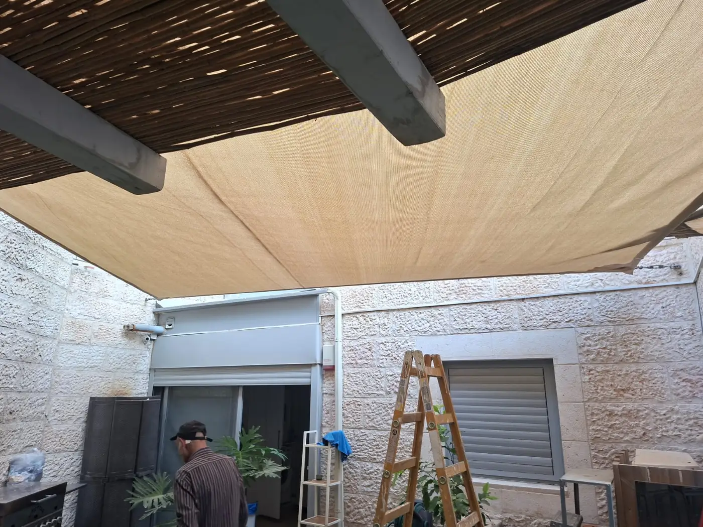 רשת צל מתוחה מתחת לפרגולת עץ בחצר